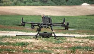 SENSYS R3 drone magnetometer system mounted beneath a drone during a survey over open farmland.