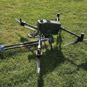 Multi-rotor survey drone equipped with a geophysical sensor payload positioned on grass, ready for airborne data collection and mapping operations.
